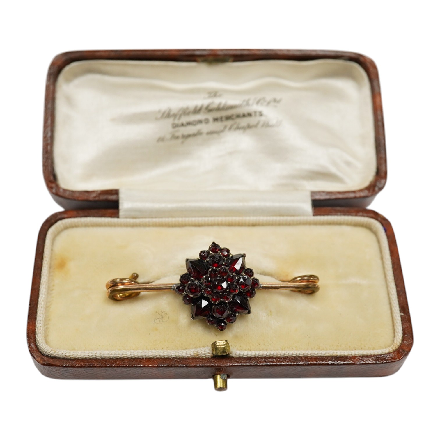 A rolled gold and garnet cluster set bar brooch, 44mm (adapted). Condition - poor to fair